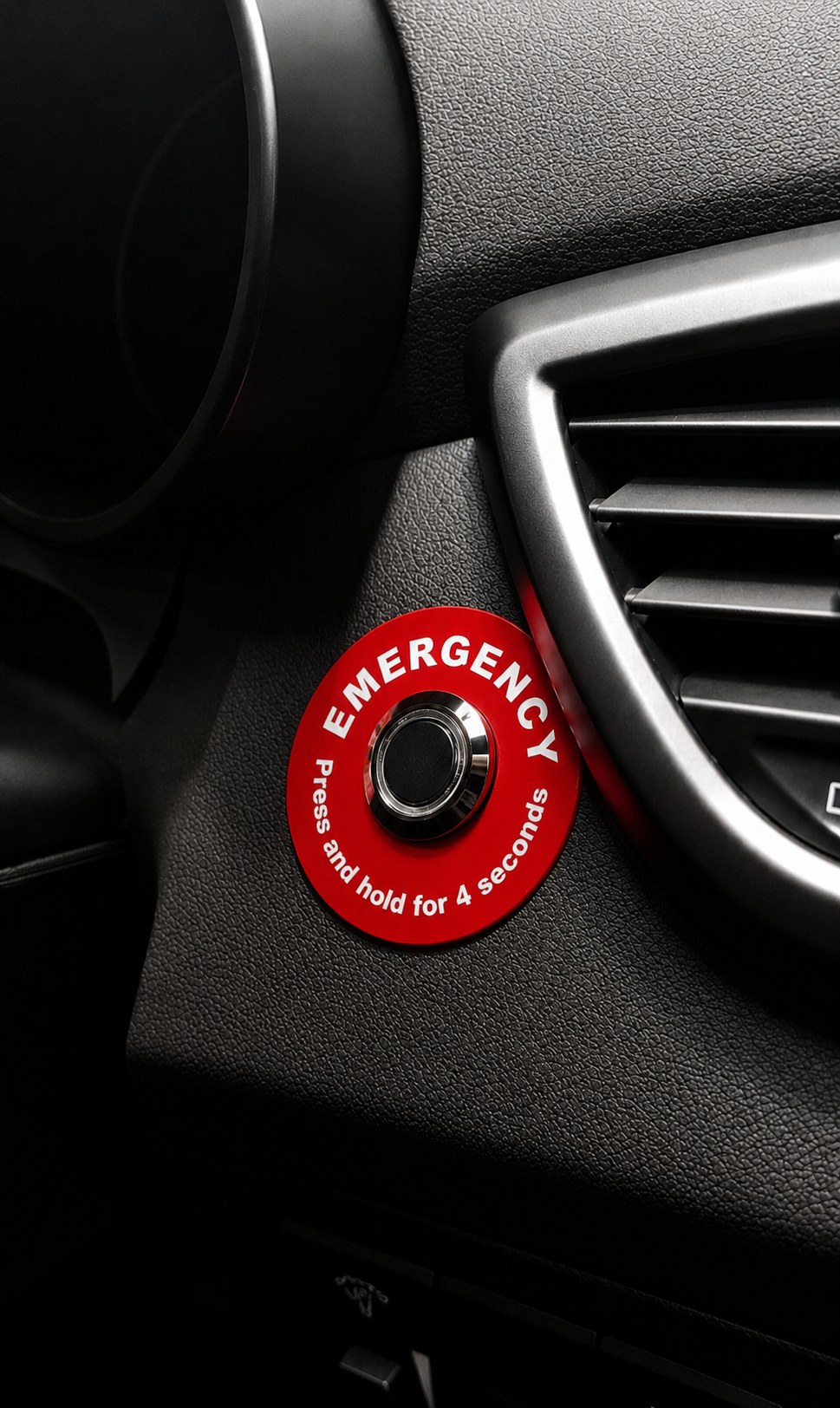 Sensium in-vehicle panic button — red EMERGENCY disc mounted on a vehicle dashboard, labelled 'Press and hold for 4 seconds'.