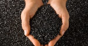 A hand holds a portion of these durable and environmentally responsible pellets, ready for green manufacturing solutions