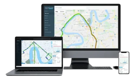 An array of devices including a laptop, a desktop monitor, and a smartphone displaying a navigation map with route information from Sensium's mapping software.